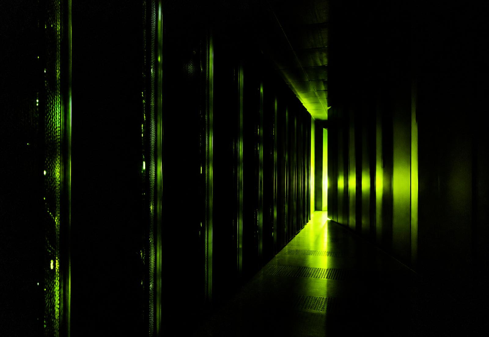 Dark data centre corridor lit by green light strips